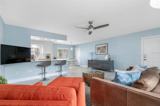 living room with ceiling fan and baseboards