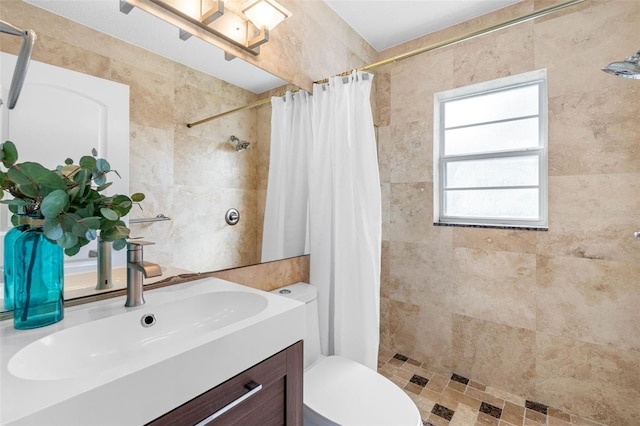 bathroom featuring tiled shower, vanity, toilet, and tile walls