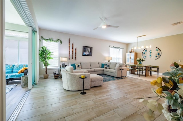 living room with ceiling fan with notable chandelier