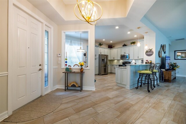 interior space featuring white cabinets, stainless steel appliances, a chandelier, kitchen peninsula, and a kitchen breakfast bar