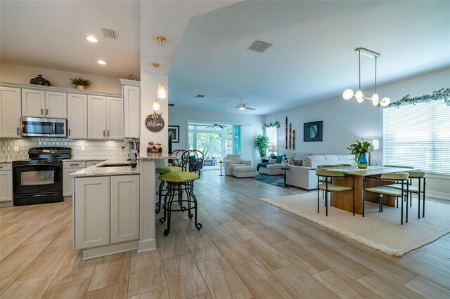 kitchen featuring black electric range, hanging light fixtures, kitchen peninsula, ceiling fan, and white cabinets