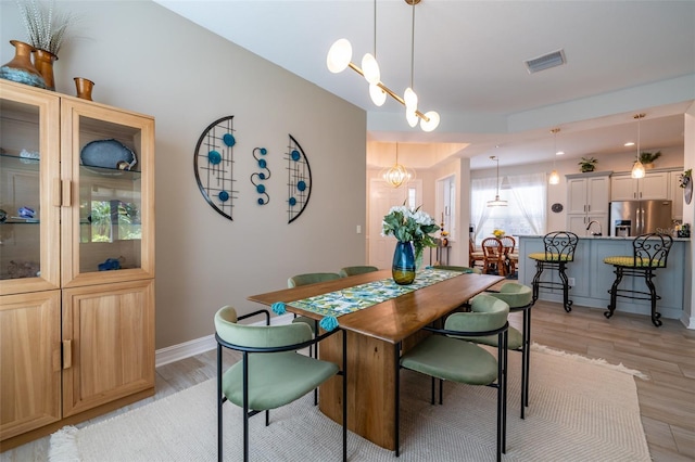 dining area with sink, a chandelier, and light hardwood / wood-style flooring