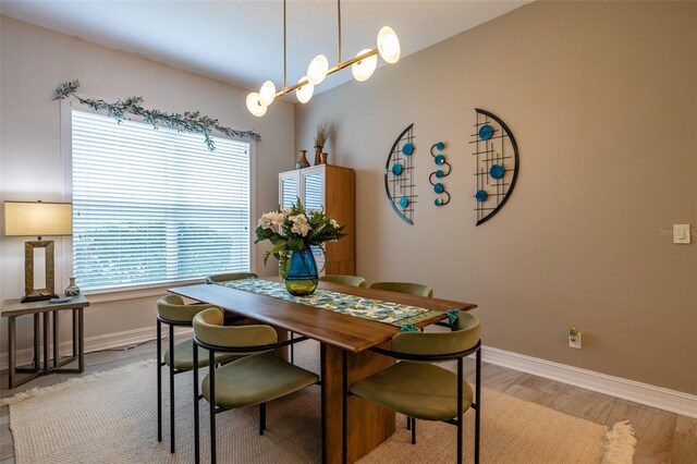 dining area with light hardwood / wood-style flooring and a chandelier