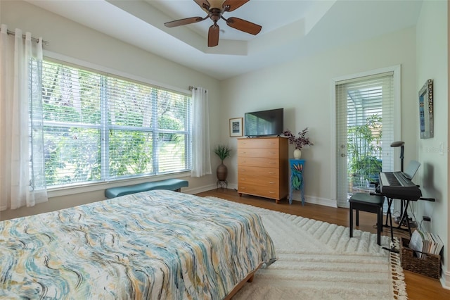 bedroom featuring ceiling fan, a raised ceiling, and wood-type flooring