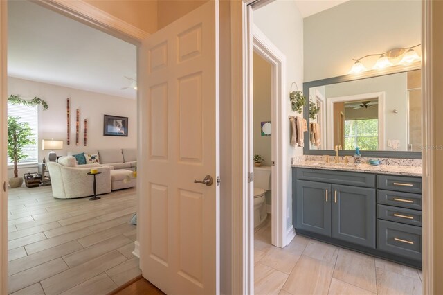 bathroom with vanity, toilet, hardwood / wood-style floors, and ceiling fan