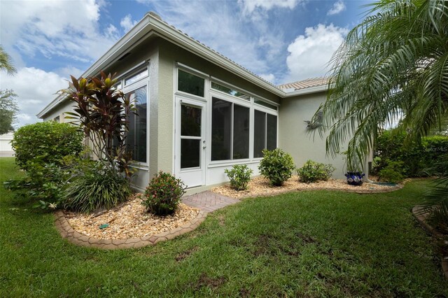 view of property exterior featuring a yard and a sunroom