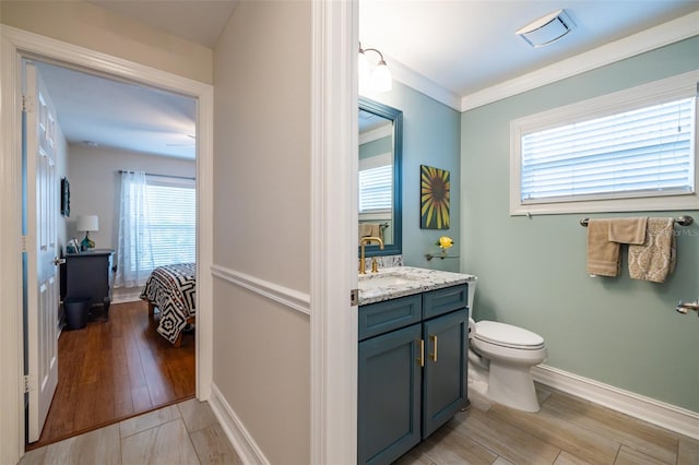 bathroom featuring toilet, hardwood / wood-style flooring, ornamental molding, and vanity