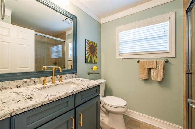 bathroom with vanity, toilet, ornamental molding, and walk in shower