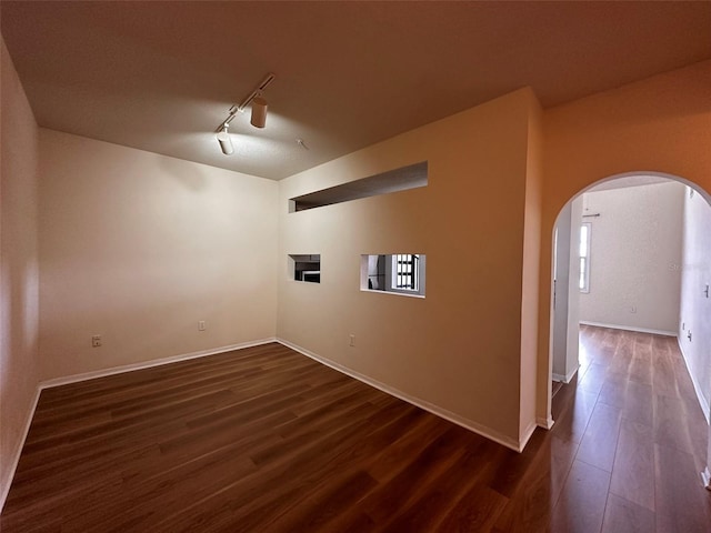 empty room featuring dark wood-type flooring and track lighting