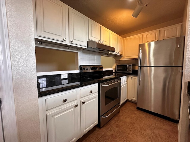 kitchen with decorative backsplash, stainless steel appliances, white cabinets, and dark tile patterned flooring