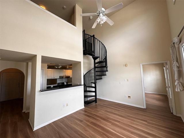 kitchen with a towering ceiling, ceiling fan, light brown cabinetry, and dark hardwood / wood-style floors