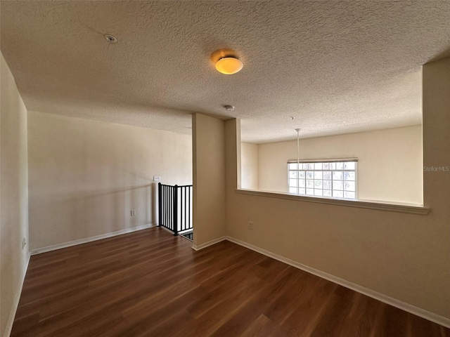 spare room featuring a textured ceiling and dark hardwood / wood-style floors