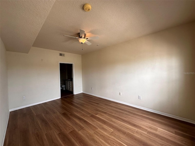 spare room with ceiling fan, a textured ceiling, and dark wood-type flooring