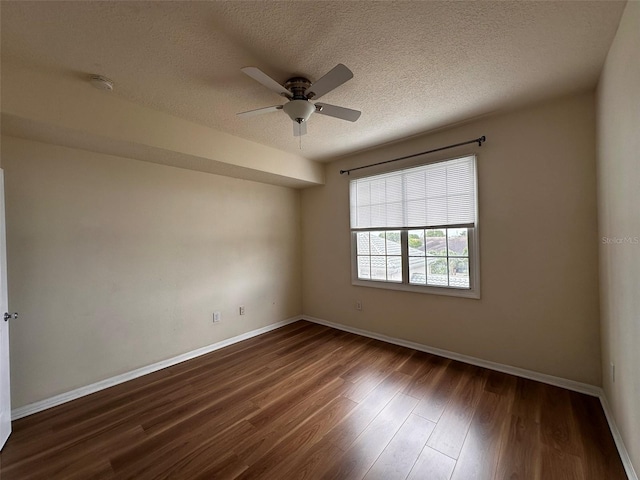 spare room with ceiling fan, a textured ceiling, and dark wood-type flooring