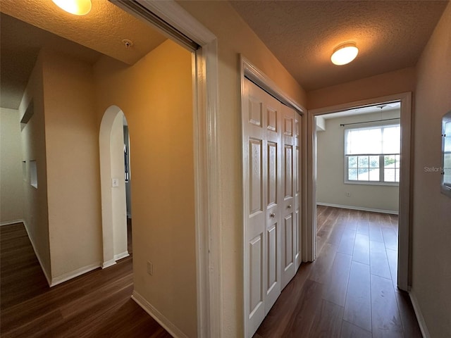 hallway with a textured ceiling and dark hardwood / wood-style floors