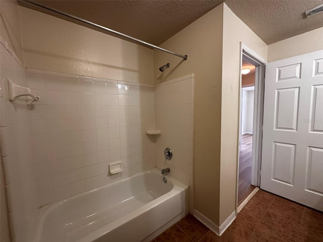 bathroom with a textured ceiling, tiled shower / bath combo, and tile patterned flooring