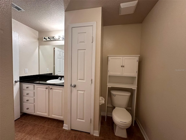 bathroom featuring tile patterned flooring, a textured ceiling, vanity, and toilet