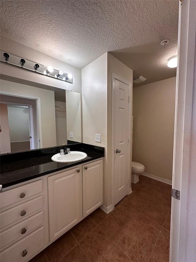 bathroom with vanity, toilet, a textured ceiling, and tile patterned floors