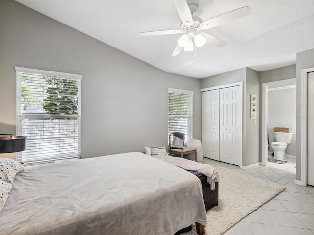 tiled bedroom with connected bathroom, ceiling fan, and a closet