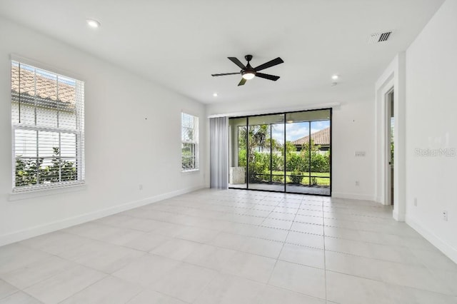 tiled spare room featuring ceiling fan and a healthy amount of sunlight