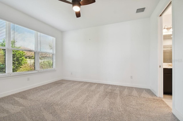 carpeted spare room featuring ceiling fan and a wealth of natural light