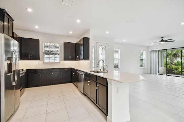 kitchen featuring sink, kitchen peninsula, appliances with stainless steel finishes, light tile patterned floors, and ceiling fan