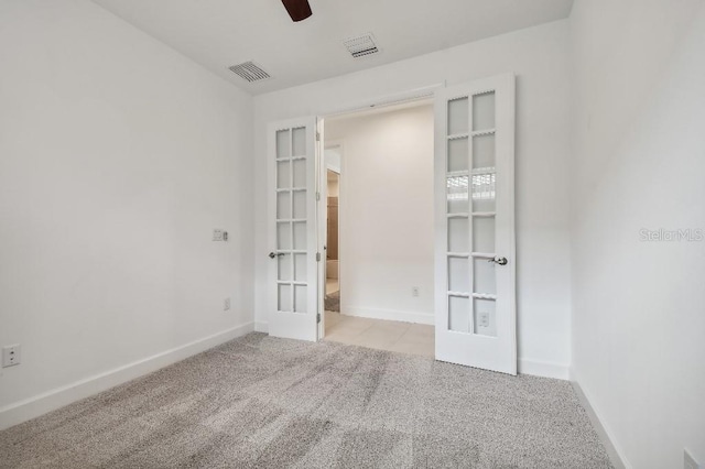 spare room with light colored carpet, ceiling fan, and french doors