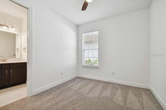 unfurnished bedroom featuring ceiling fan, light colored carpet, ensuite bathroom, and sink