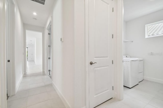 hallway with independent washer and dryer and light tile patterned floors