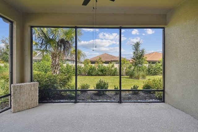 unfurnished sunroom featuring ceiling fan and plenty of natural light