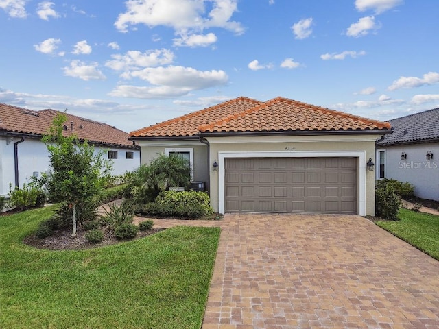 mediterranean / spanish home with a garage and a front lawn