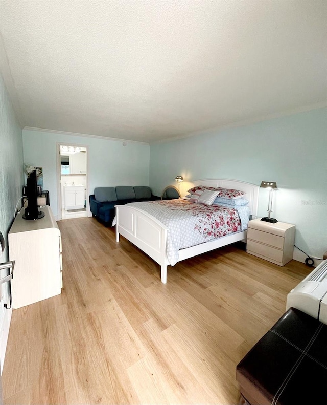 bedroom featuring ensuite bathroom, a textured ceiling, and light hardwood / wood-style flooring