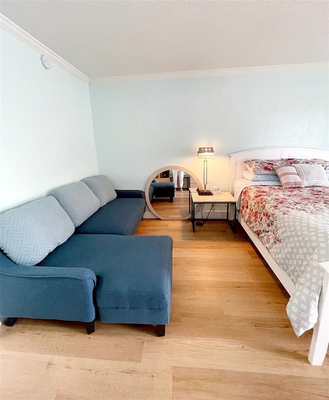 bedroom with hardwood / wood-style floors, ornamental molding, and a textured ceiling