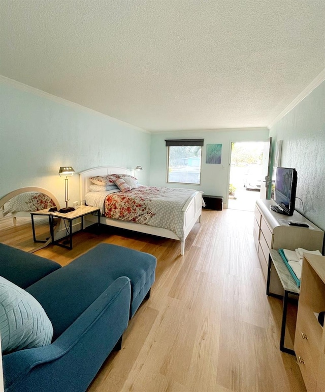 bedroom featuring ornamental molding, light hardwood / wood-style flooring, and a textured ceiling