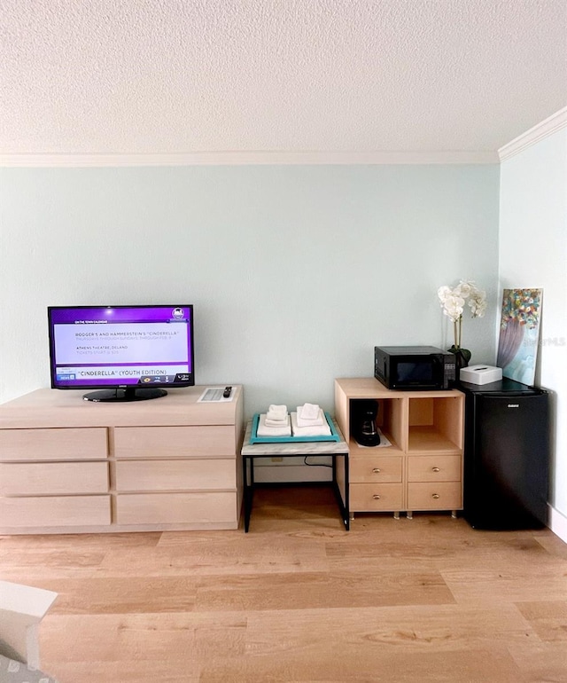 bedroom with fridge, crown molding, light hardwood / wood-style floors, and a textured ceiling