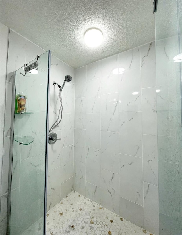 bathroom featuring a tile shower and a textured ceiling