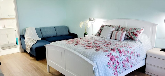bedroom featuring light wood finished floors and a sink
