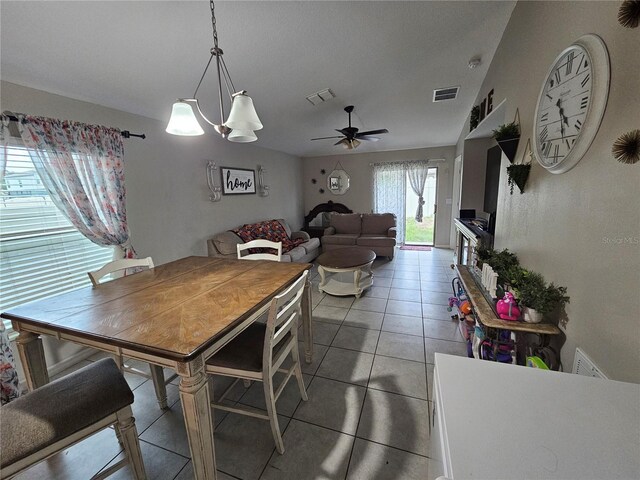 dining room with ceiling fan with notable chandelier and tile patterned floors