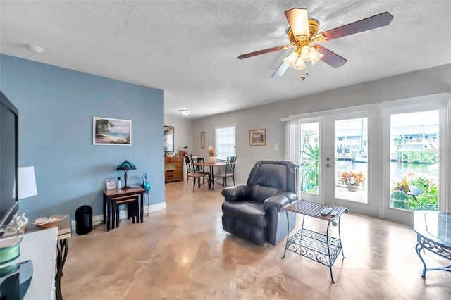 living room featuring ceiling fan and a textured ceiling