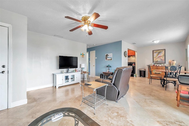 living room with ceiling fan and a textured ceiling