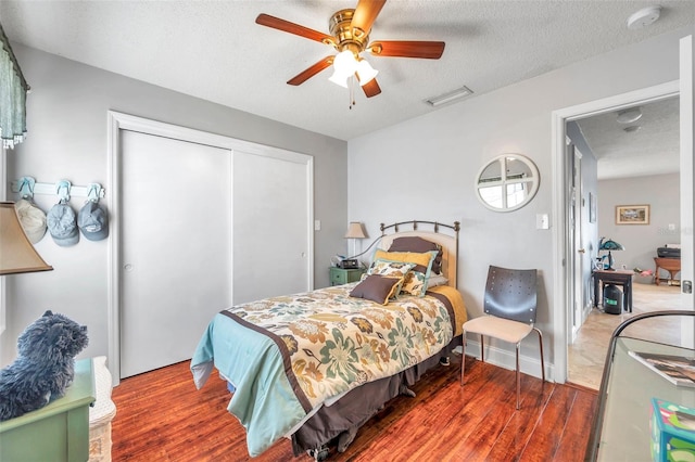 bedroom with wood-type flooring, a textured ceiling, a closet, and ceiling fan