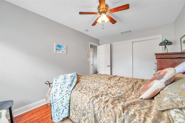 bedroom featuring ceiling fan, a textured ceiling, a closet, and hardwood / wood-style floors