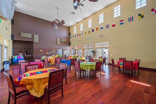 dining space with wood-type flooring, a high ceiling, and ceiling fan