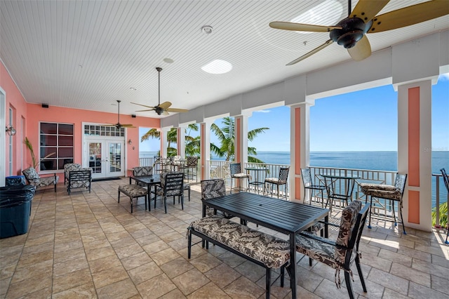 interior space with a water view, ceiling fan, and french doors