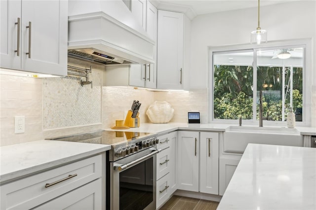 kitchen featuring premium range hood, tasteful backsplash, white cabinets, stainless steel range, and light stone counters