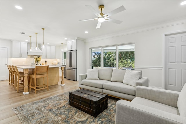 living room featuring ornamental molding, ceiling fan, and light hardwood / wood-style flooring