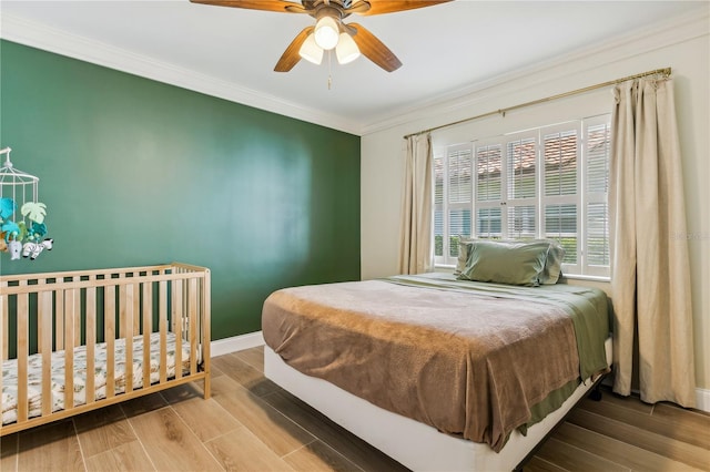 bedroom featuring hardwood / wood-style flooring, crown molding, and ceiling fan