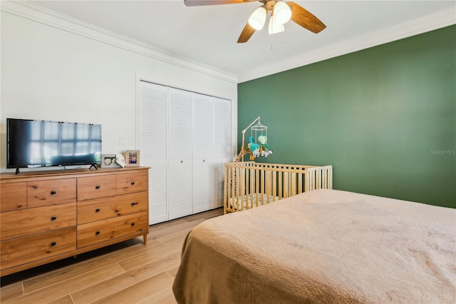 bedroom with crown molding, ceiling fan, a closet, and light hardwood / wood-style flooring