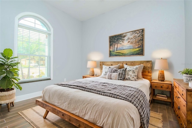 bedroom with dark hardwood / wood-style floors and multiple windows