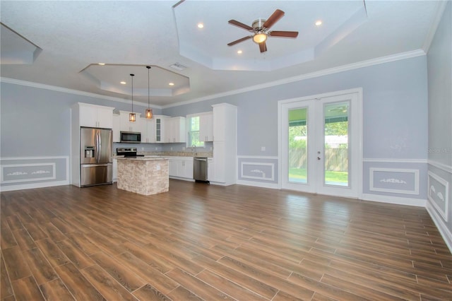 kitchen featuring a center island, stainless steel appliances, a raised ceiling, and hanging light fixtures